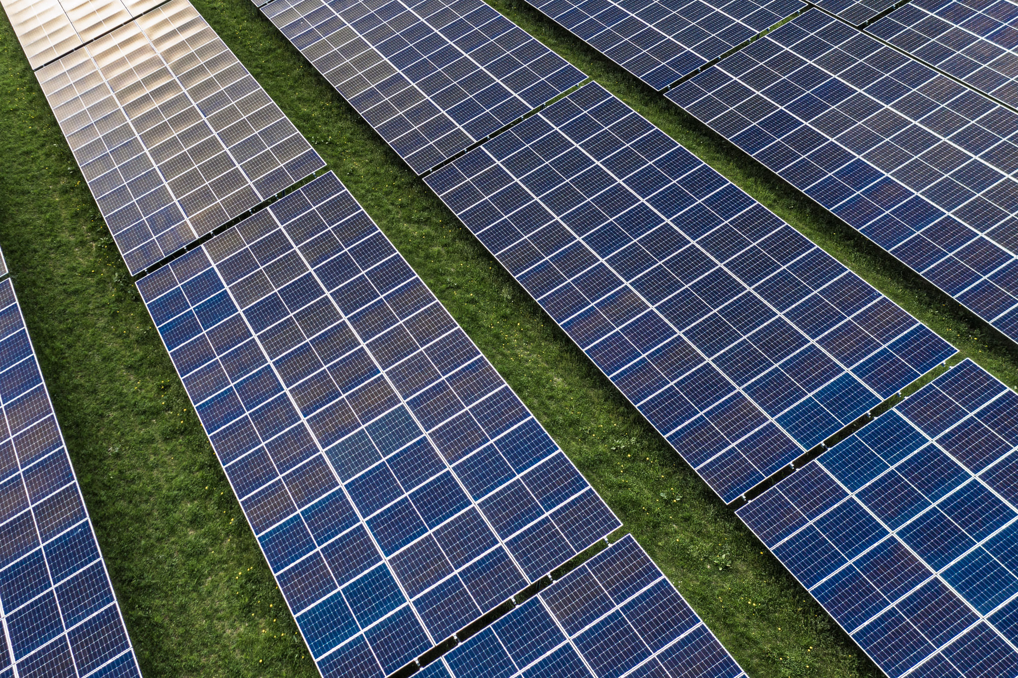 Luftaufnahme eines Solarparks in Bayern bei Traunstein – gleichmäßig angeordnete Photovoltaik-Module auf grüner Wiese, Businessfotografie für Unternehmen im Bereich erneuerbare Energien